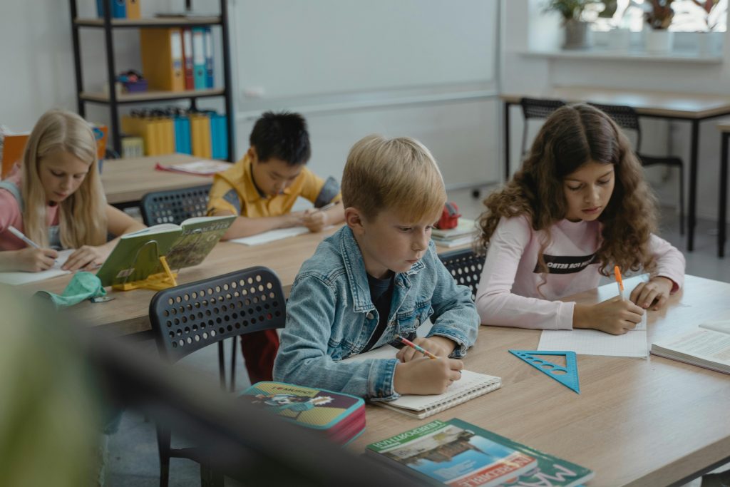 A group of children focused on studying in a classroom with books and stationery.
